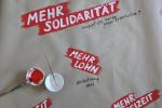 Schriftzüge auf Wandzeitung: Mehr Solidarität, Mehr Lohn ...